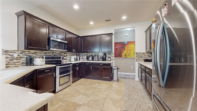 kitchen with decorative backsplash, dark brown cabinets, light tile patterned flooring, and appliances with stainless steel finishes