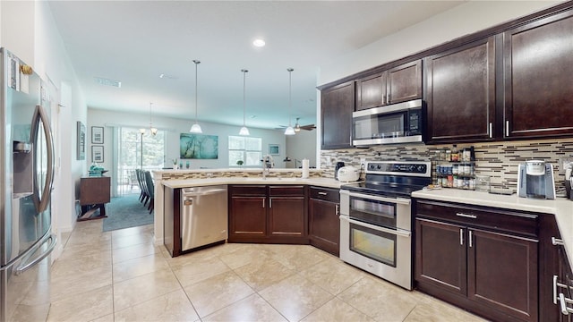 kitchen with pendant lighting, decorative backsplash, kitchen peninsula, and stainless steel appliances