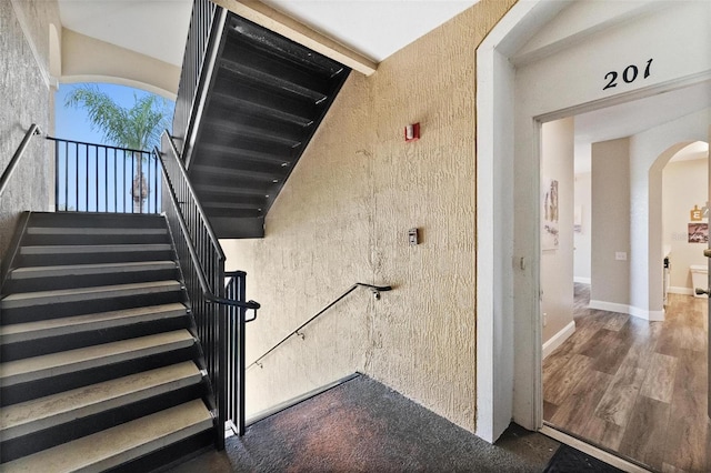 staircase featuring beamed ceiling and hardwood / wood-style flooring