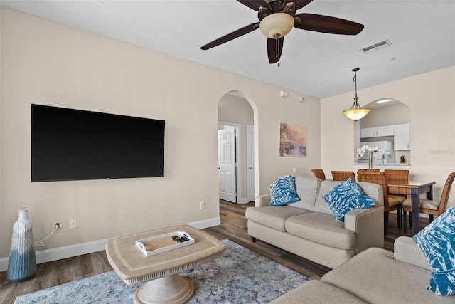 living room with dark hardwood / wood-style flooring and ceiling fan