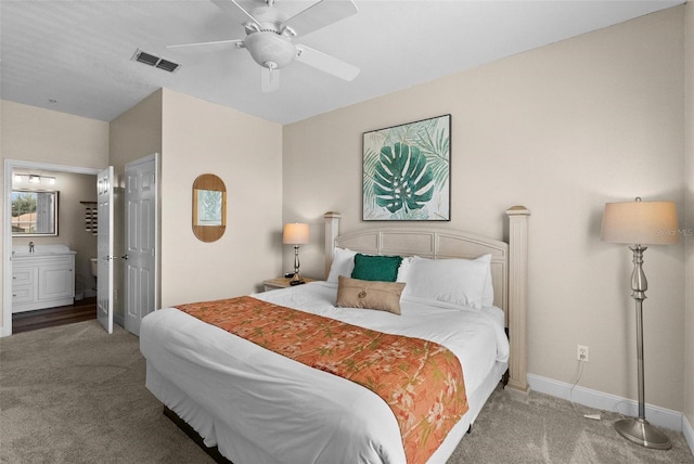 carpeted bedroom with ensuite bath and ceiling fan