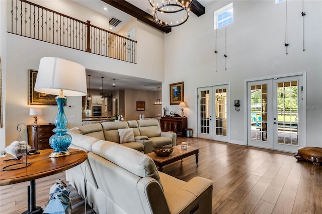 living room featuring beam ceiling, french doors, high vaulted ceiling, a notable chandelier, and hardwood / wood-style flooring