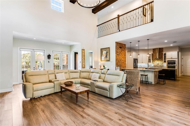 living room featuring french doors, a towering ceiling, and light wood-type flooring