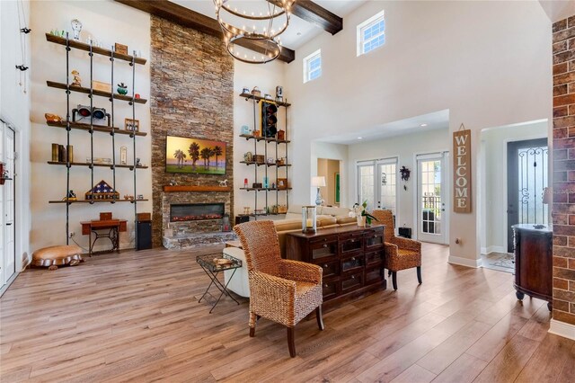 living room with a fireplace, beam ceiling, light wood-type flooring, and a high ceiling