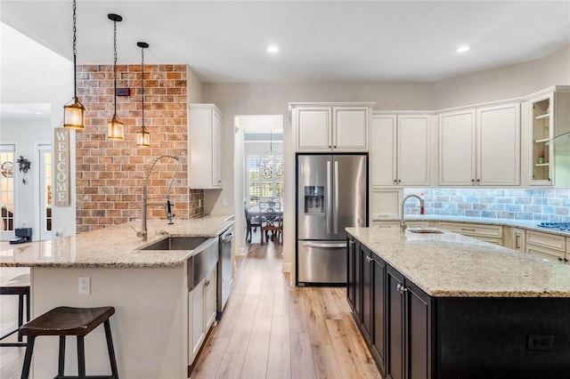 kitchen featuring light stone counters, light hardwood / wood-style floors, decorative light fixtures, and appliances with stainless steel finishes