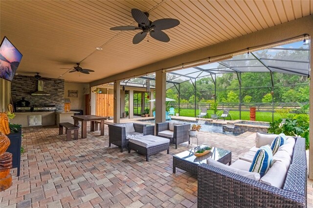 view of patio / terrace featuring a lanai, ceiling fan, exterior kitchen, and an outdoor living space