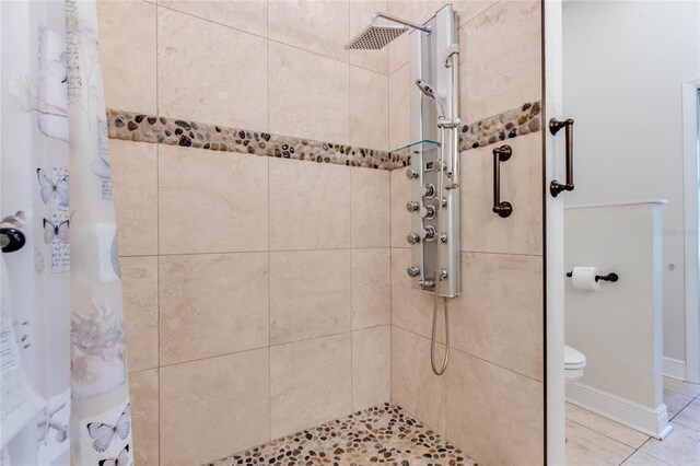 bathroom with a shower with shower curtain, tile patterned flooring, and toilet