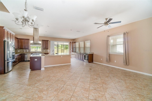 kitchen with appliances with stainless steel finishes, island range hood, decorative backsplash, hanging light fixtures, and a center island