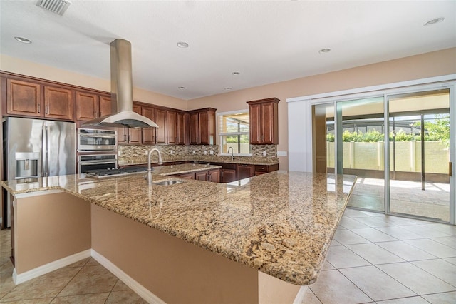 kitchen featuring a spacious island, sink, island exhaust hood, light stone countertops, and decorative backsplash