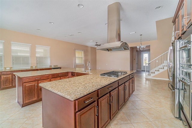 kitchen featuring appliances with stainless steel finishes, sink, island exhaust hood, a kitchen island with sink, and light stone countertops