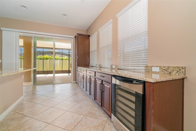 bar with light tile patterned flooring, light stone countertops, and beverage cooler