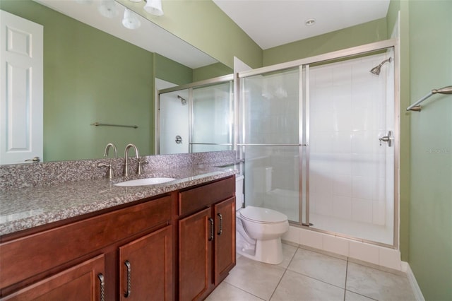 bathroom with vanity, a shower with shower door, tile patterned floors, and toilet