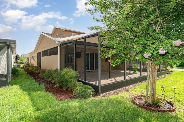 back of property with a yard and glass enclosure