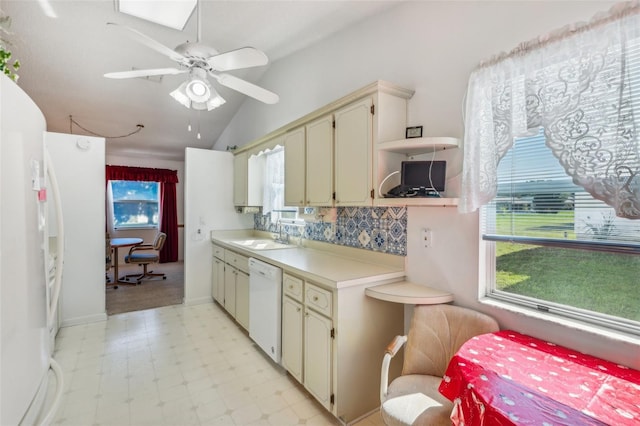 kitchen with lofted ceiling, white appliances, cream cabinets, sink, and ceiling fan