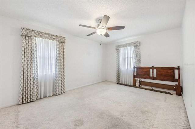 carpeted spare room featuring ceiling fan and a textured ceiling