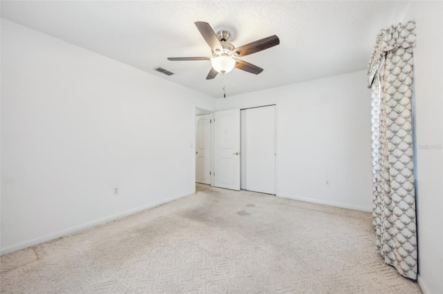 unfurnished bedroom featuring ceiling fan, light carpet, and a closet