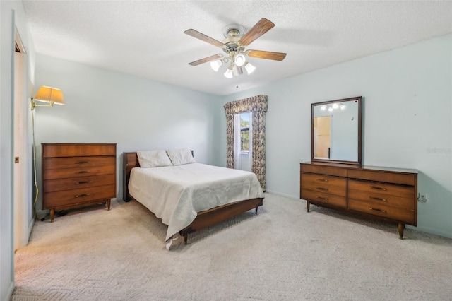 bedroom with ceiling fan, light colored carpet, and a textured ceiling