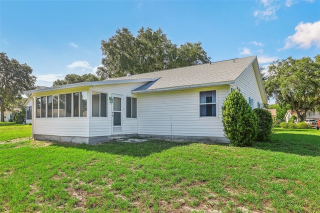 rear view of property featuring a yard and a sunroom