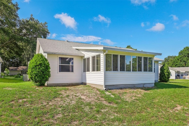 rear view of house with central AC unit, a lawn, and a sunroom