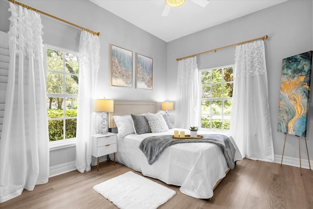 bedroom with hardwood / wood-style flooring, ceiling fan, and multiple windows