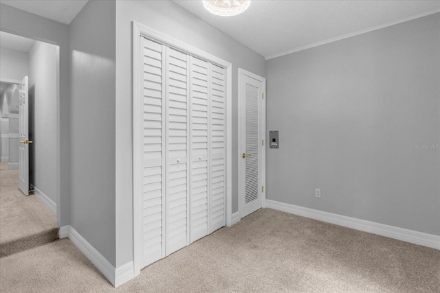 unfurnished bedroom with carpet floors, a textured ceiling, and a closet