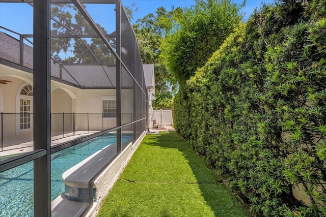 view of swimming pool featuring a lawn and glass enclosure