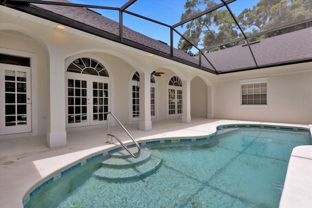 view of swimming pool with glass enclosure, ceiling fan, a patio area, and french doors