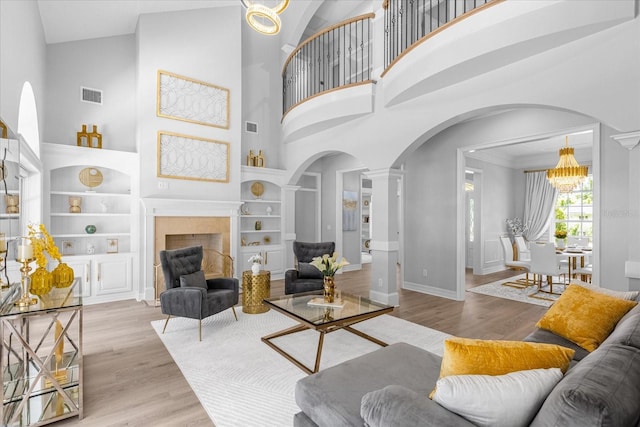 living room with built in features, a high ceiling, and an inviting chandelier