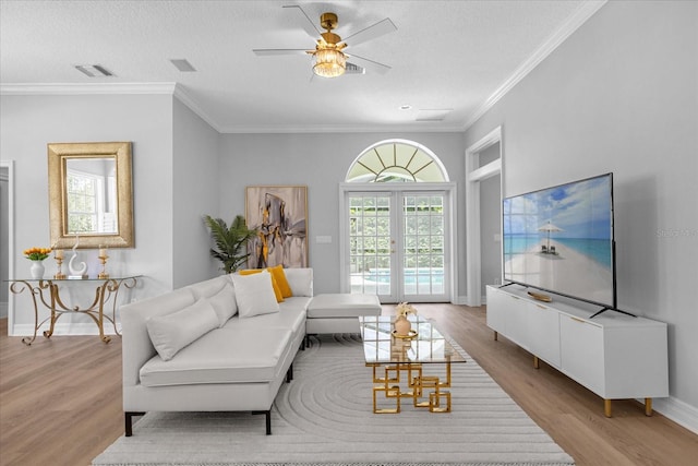 living room featuring french doors, ceiling fan, ornamental molding, a textured ceiling, and light hardwood / wood-style floors