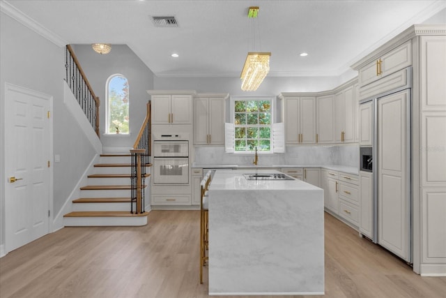 kitchen featuring pendant lighting, backsplash, paneled built in refrigerator, a kitchen island, and light stone counters