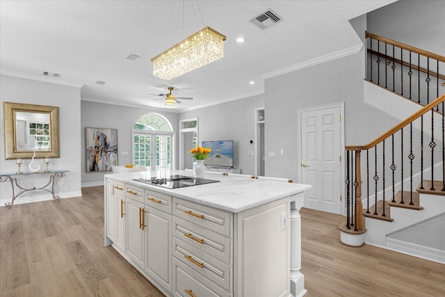 kitchen with ceiling fan with notable chandelier, black electric cooktop, decorative light fixtures, a kitchen island, and white cabinetry