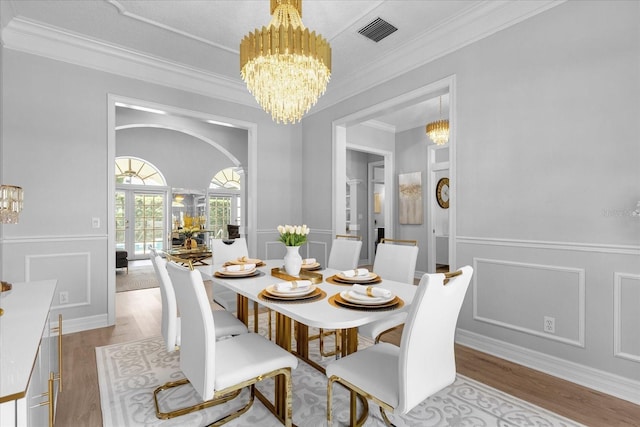 dining area featuring light hardwood / wood-style flooring, ornamental molding, and a notable chandelier