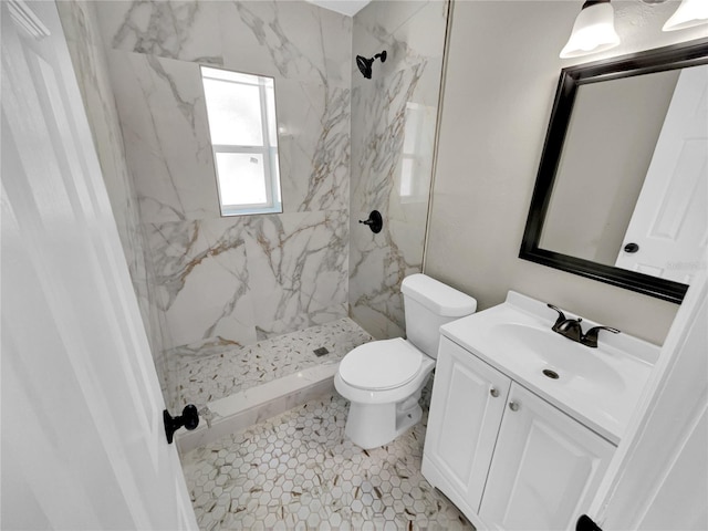 bathroom with a tile shower, tile patterned flooring, vanity, and toilet