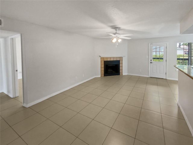 unfurnished living room featuring a tiled fireplace, light tile patterned floors, and ceiling fan