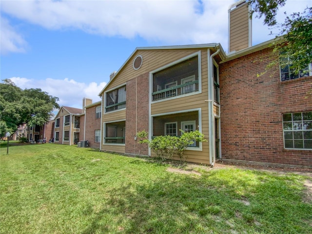 rear view of property with a yard and central air condition unit