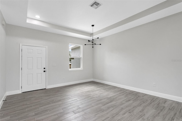 empty room with a tray ceiling and hardwood / wood-style flooring