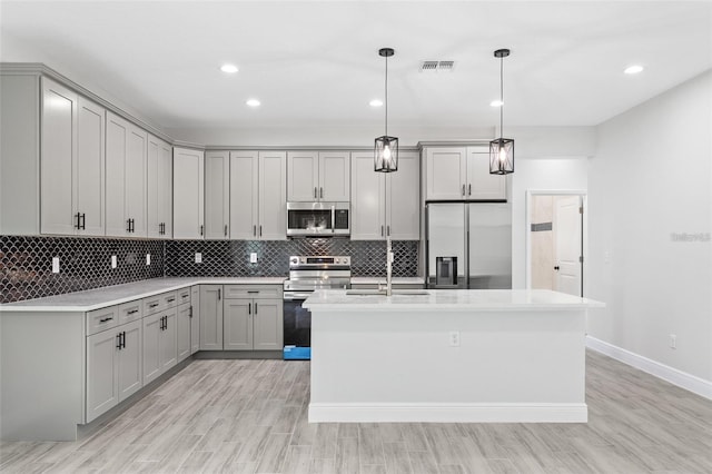 kitchen featuring hanging light fixtures, a center island with sink, appliances with stainless steel finishes, and backsplash