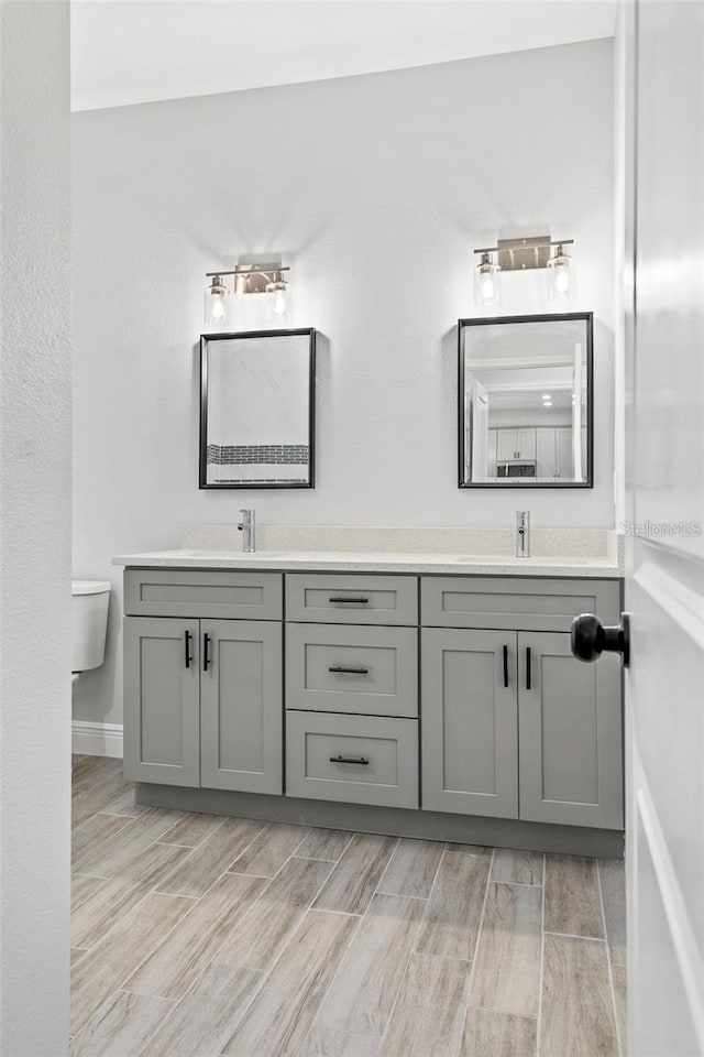 bathroom featuring dual vanity, hardwood / wood-style flooring, and toilet