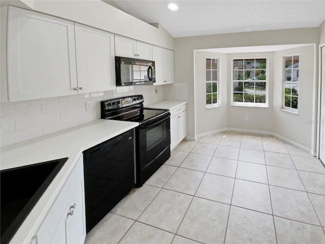 kitchen featuring decorative backsplash, black appliances, light tile patterned floors, white cabinets, and lofted ceiling