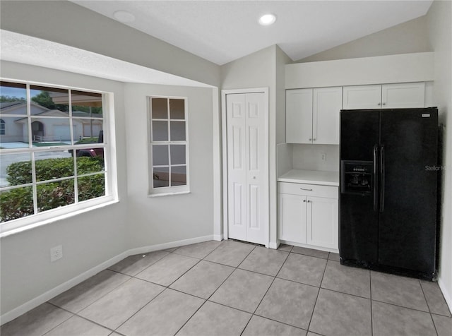 kitchen featuring white cabinetry, black fridge, lofted ceiling, and light tile patterned floors