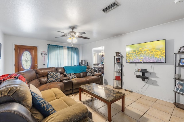 living room with light tile patterned floors, ceiling fan with notable chandelier, and a textured ceiling