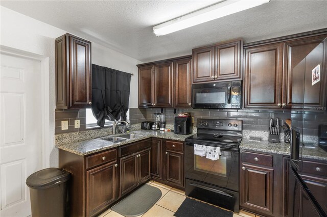 kitchen featuring sink, light tile patterned floors, tasteful backsplash, light stone counters, and black appliances