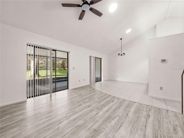 unfurnished room featuring ceiling fan with notable chandelier, lofted ceiling, and light hardwood / wood-style flooring