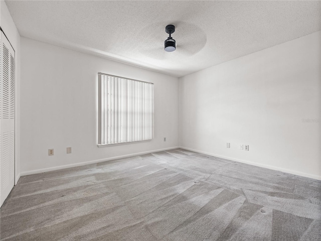 carpeted spare room featuring ceiling fan and a textured ceiling