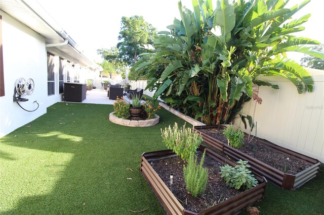 view of yard with a garden, a fenced backyard, and a patio area