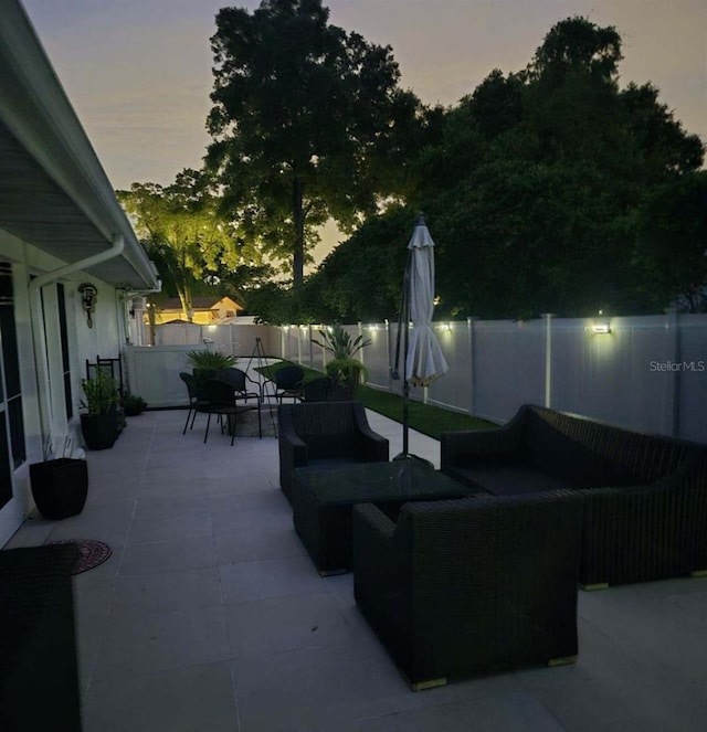 patio terrace at dusk featuring outdoor lounge area and a fenced backyard