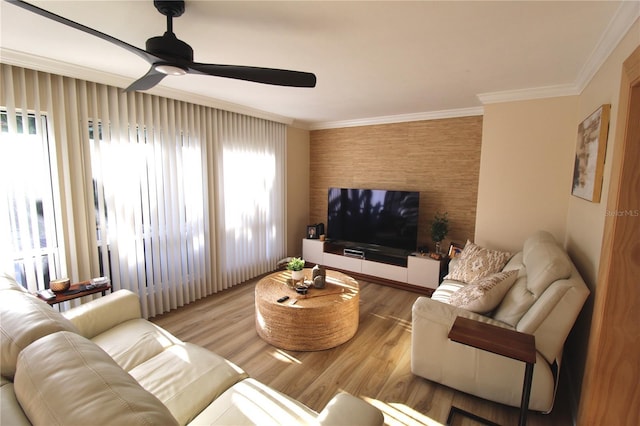 living area with wood finished floors, ceiling fan, and ornamental molding