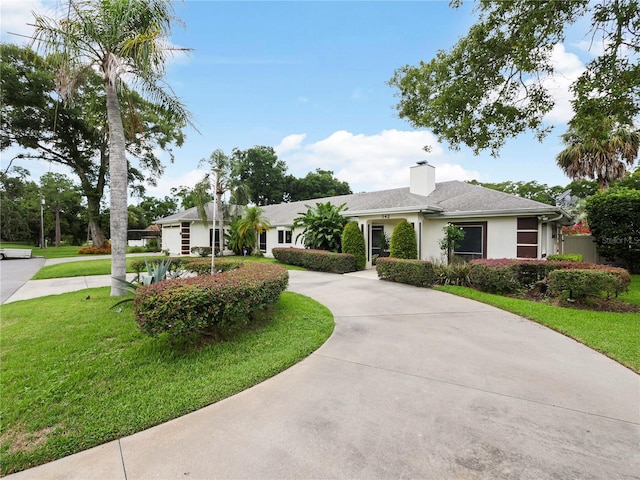 single story home with stucco siding, roof with shingles, concrete driveway, a front yard, and a chimney