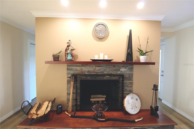 interior details featuring baseboards, a stone fireplace, wood finished floors, and crown molding