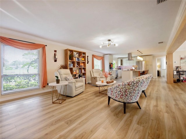 living area featuring visible vents, light wood-style floors, an inviting chandelier, and crown molding